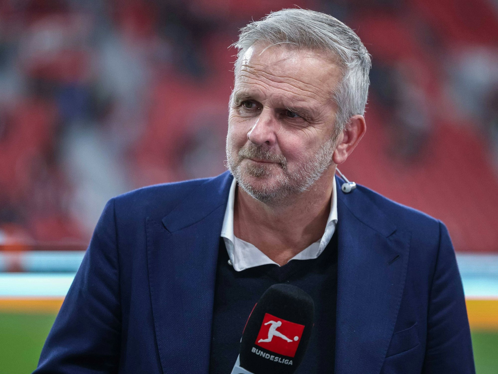 TV-Experte Dietmar Hamann hält ein Mikrofon in der Hand.