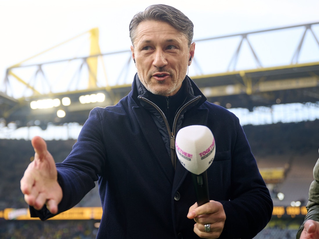 Niko Kovac streckt die Hand aus und hat in der anderen ein Mikrofon in der Hand.