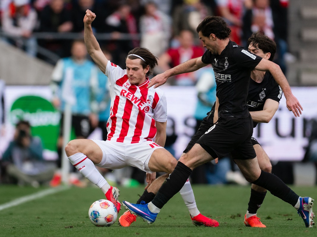 21.03.2026, Nordrhein-Westfalen, Köln: Fußball, Männer: Bundesliga, 1. FC Köln - Borussia Mönchengladbach, 27. Spieltag, RheinEnergieStadion. Jakub Kamiński (l, 1. FC Köln) und Joe Scally (Borussia Mönchengladbach) kämpfen um den Ball. Foto: Marius Becker/dpa - WICHTIGER HINWEIS: Gemäß den Vorgaben der DFL Deutsche Fußball Liga bzw. des DFB Deutscher Fußball-Bund ist es untersagt, in dem Stadion und/oder vom Spiel angefertigte Fotoaufnahmen in Form von Sequenzbildern und/oder videoähnlichen Fotostrecken zu verwerten bzw. verwerten zu lassen. +++ dpa-Bildfunk +++