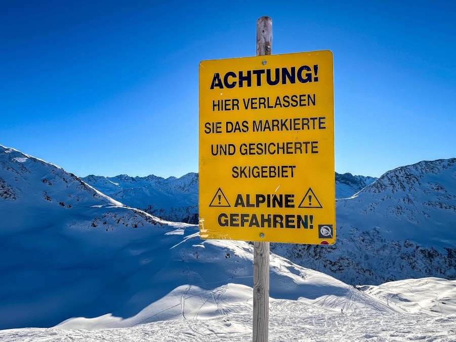 Warnschild für alpine Gefahren und Berge