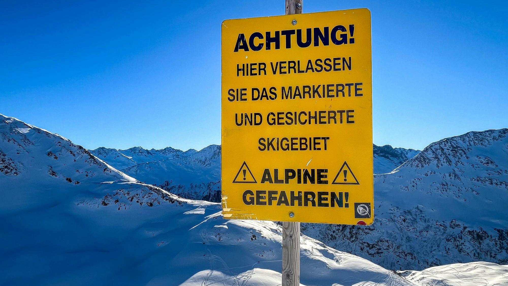 Warnschild für alpine Gefahren und Berge