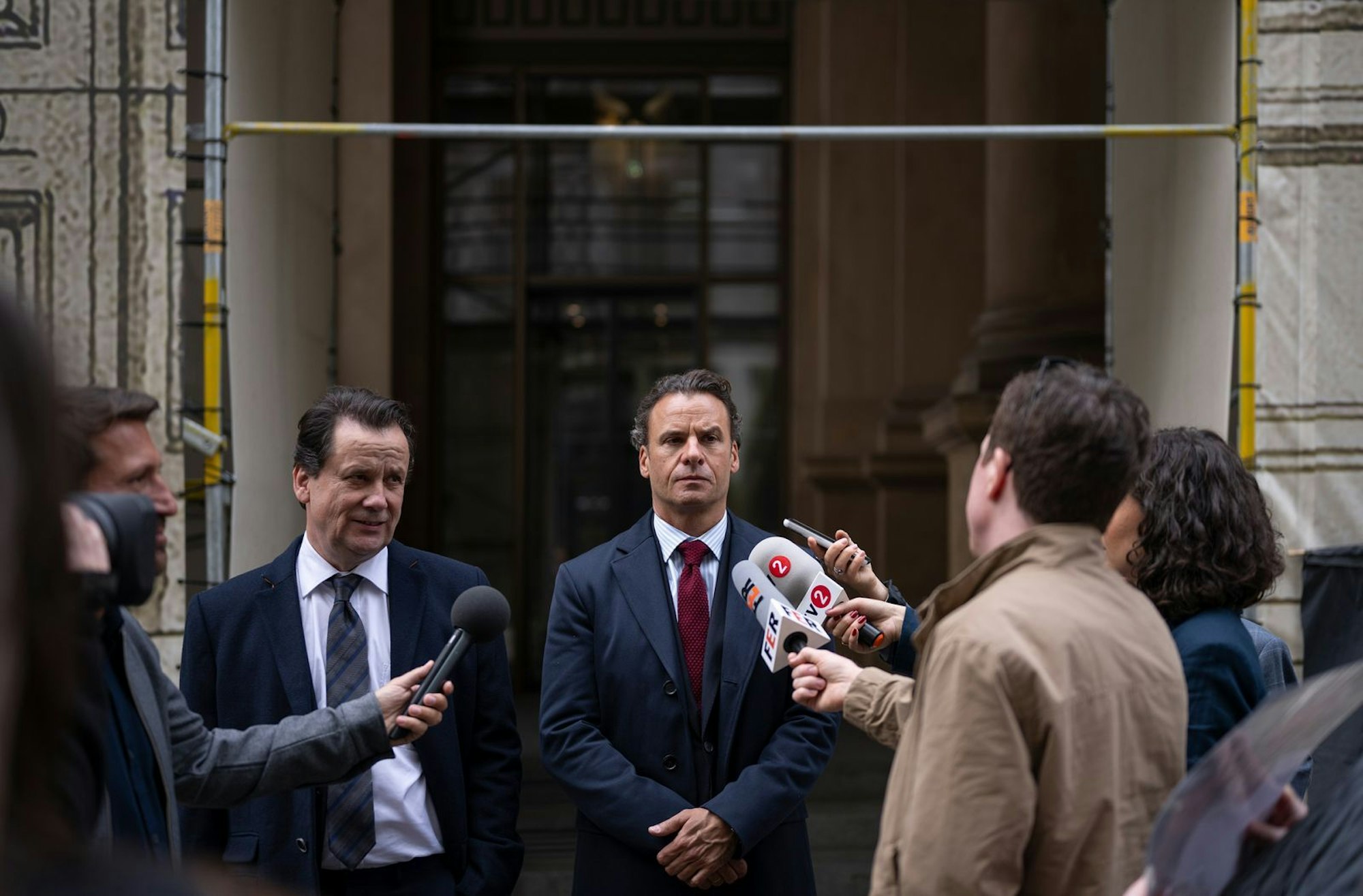 Steffen Böttcher (Stephan Luca, Mitte) und sein Anwalt (Christian Kuchenbuch, zweiter von links) müssen den Reportern beim Verlassen des Untersuchungsausschusses Fragen beantworten. (Bild: HR/ARD Degeto Film/Sommerhaus/Tatiana Vdovenko)