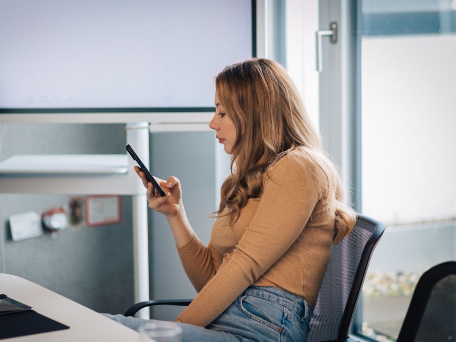 Junge Frau mit Smartphone im Büro