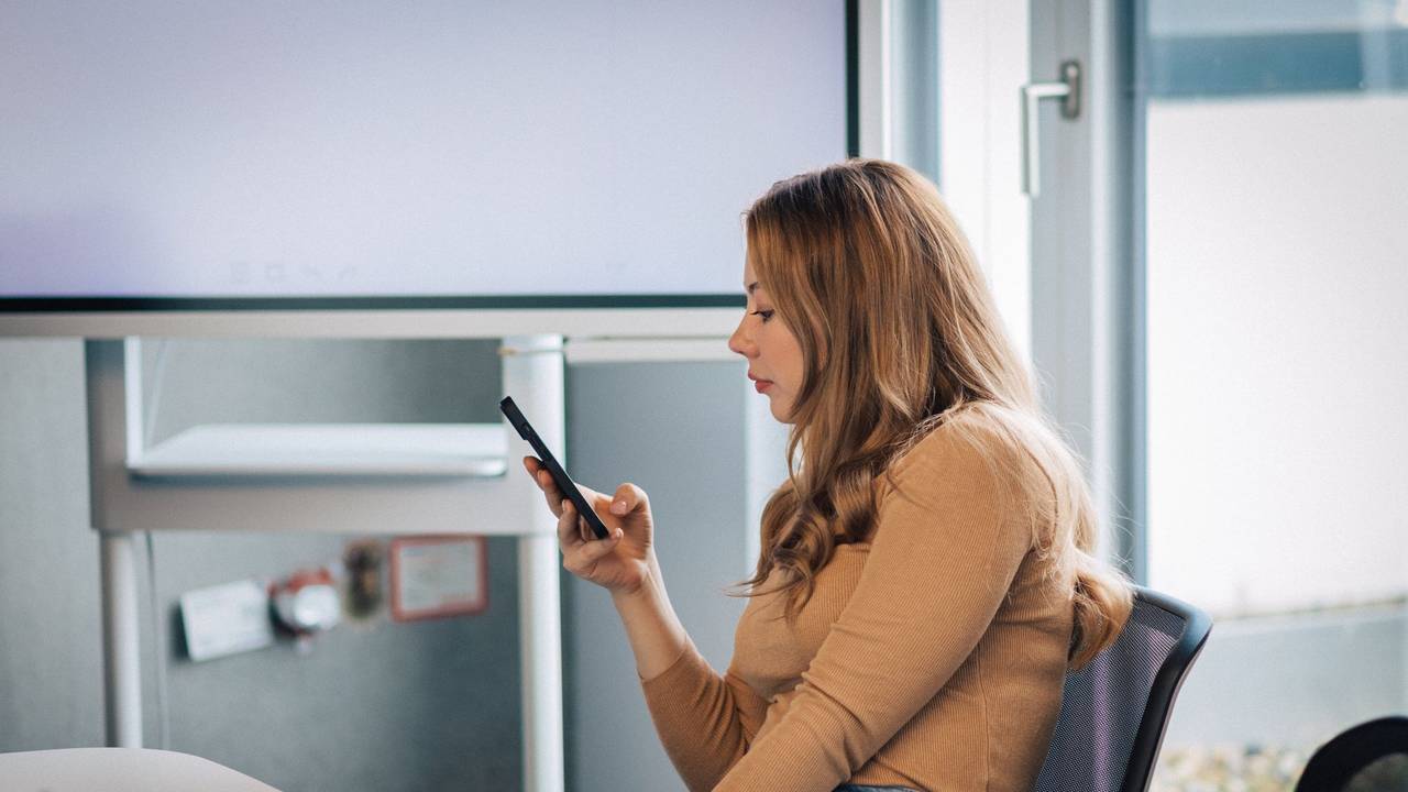 Junge Frau mit Smartphone im Büro