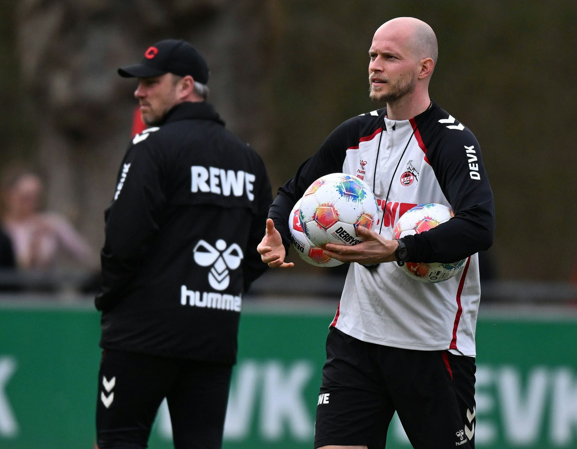 René Wagner im Training mit Bällen in der Hand, im Hintergrund steht Lukas Kwasniok.