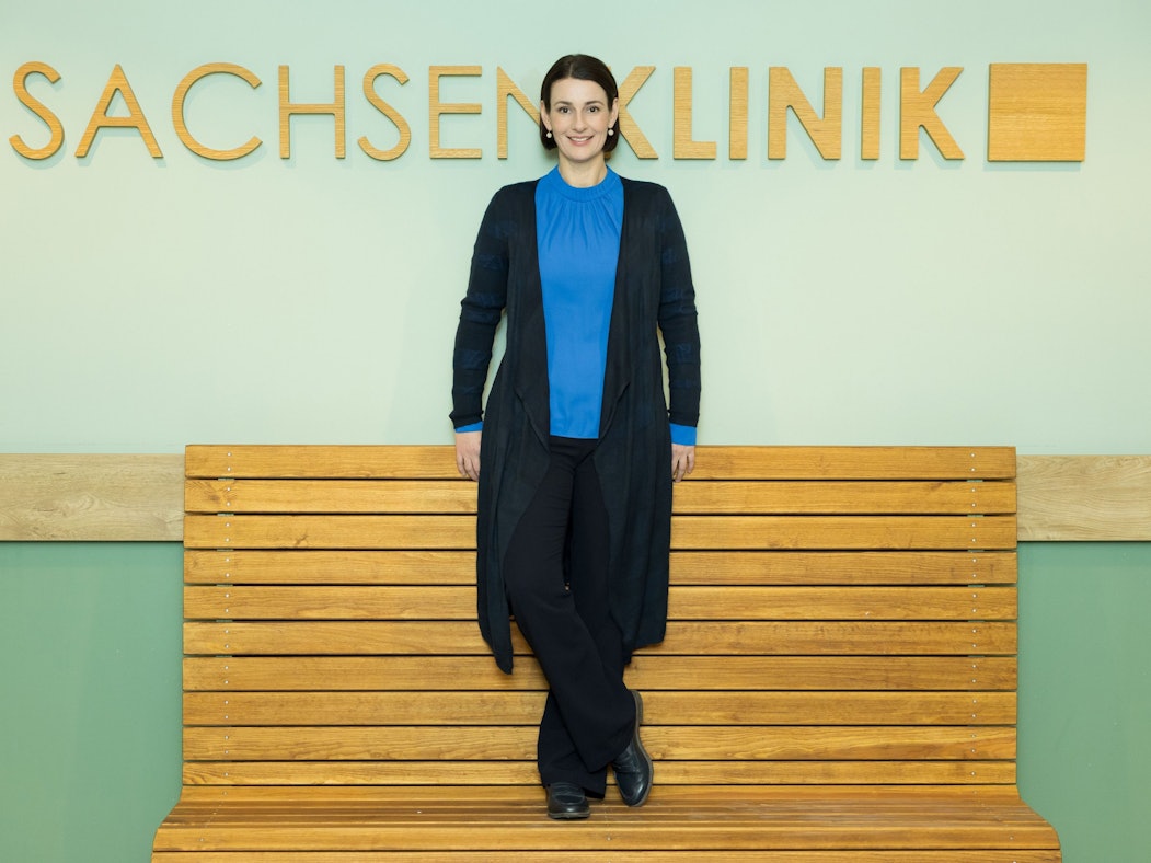 Schauspielerin Annett Renneberg steht vor einer Wand mit dem Schriftzug Sachsenklinik.
