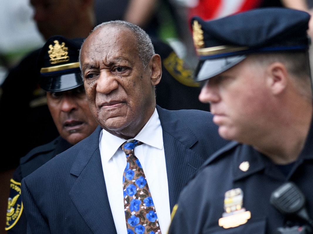 Ein dunkelhäutiger Mann geht neben zwei Polizisten.