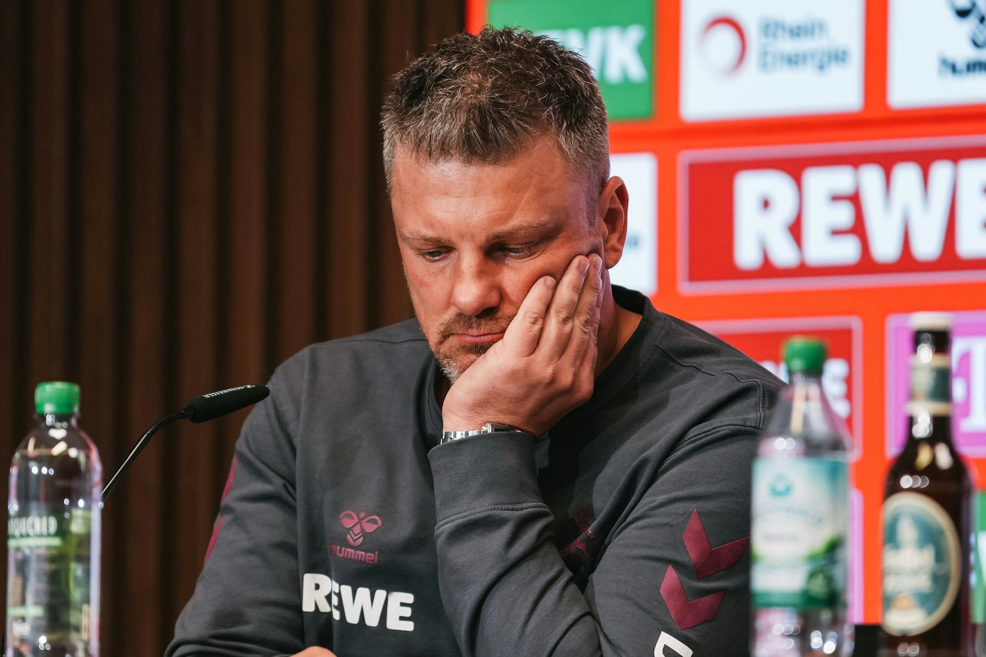 Lukas Kwasniok stützt sein Gesicht bei einer Pressekonferenz auf der linken Handinnenfläche ab.