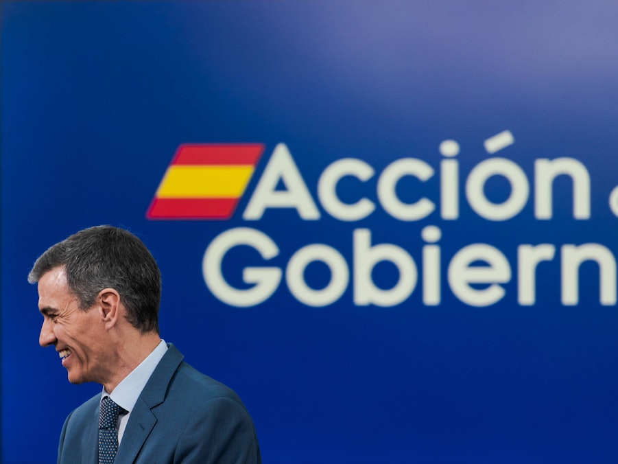 Pedro Sánchez lächelt vor blauem Banner
