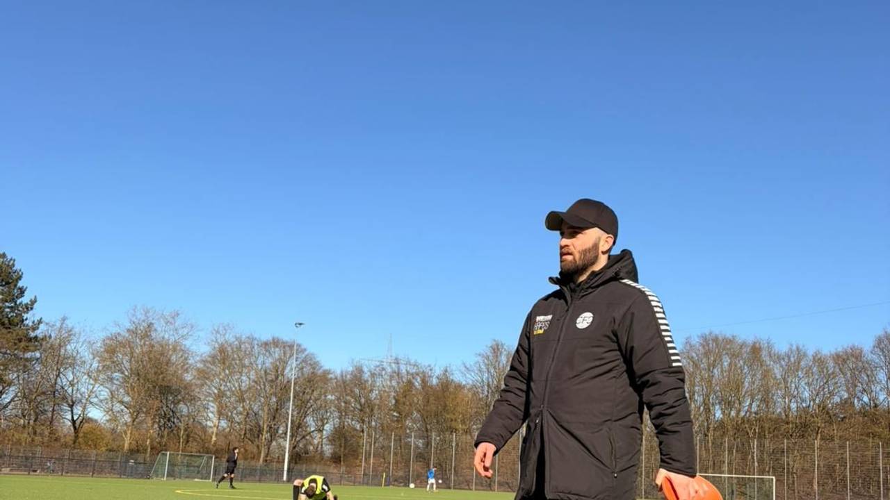 Ein Mann geht in Sportkleidung über einen Fußballplatz.