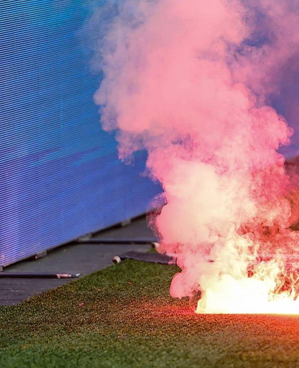 Eine Leuchtfackeln brennt an einem Fußballplatz.
