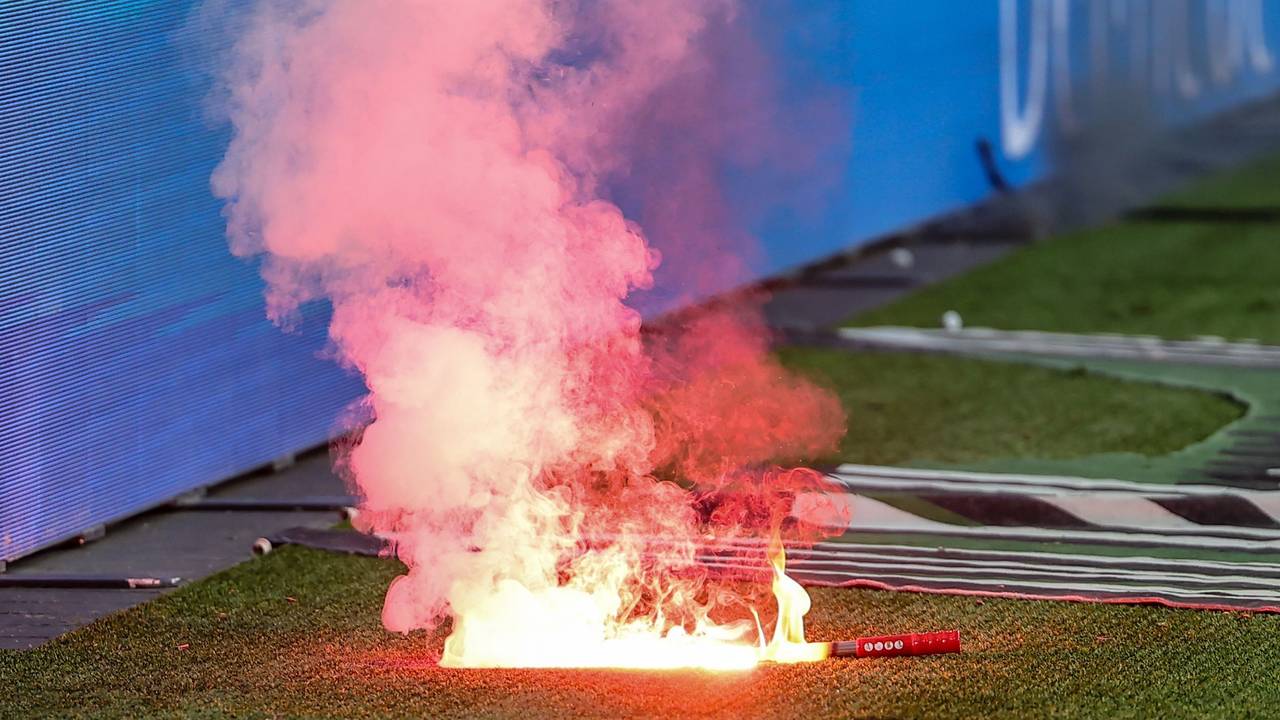 Eine Leuchtfackeln brennt an einem Fußballplatz.