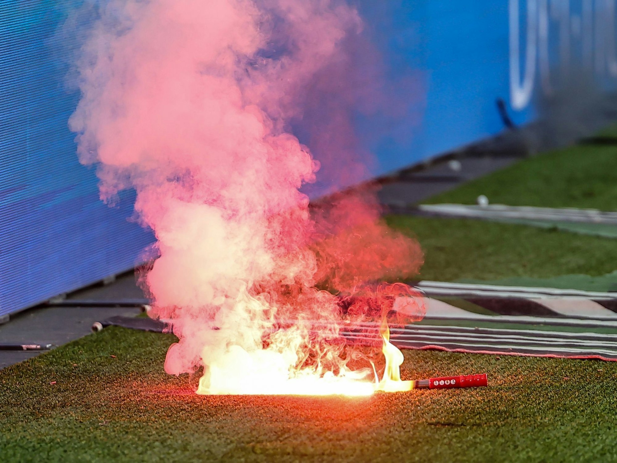 Eine Leuchtfackeln brennt an einem Fußballplatz.