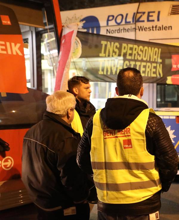 Streikende stehen mit Flaggen vor parkenden Stadtbahnen der KVB. In der Tarifrunde für den kommunalen Nahverkehr hatte Verdi für Montag zu Warnstreiks aufgerufen.