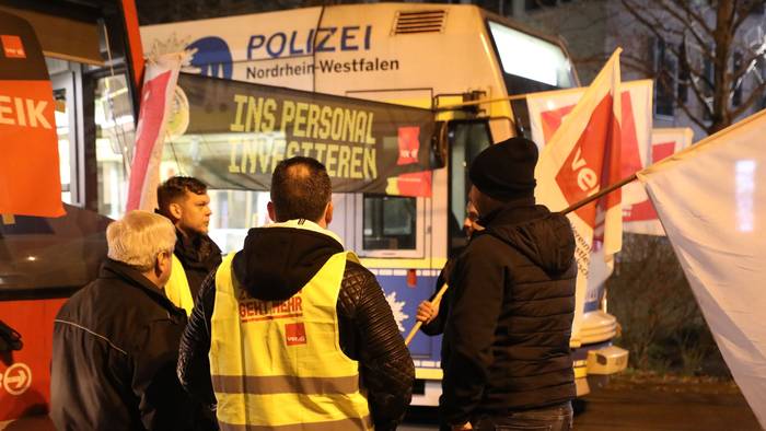 Streikende stehen mit Flaggen vor parkenden Stadtbahnen der KVB. In der Tarifrunde für den kommunalen Nahverkehr hatte Verdi für Montag zu Warnstreiks aufgerufen.