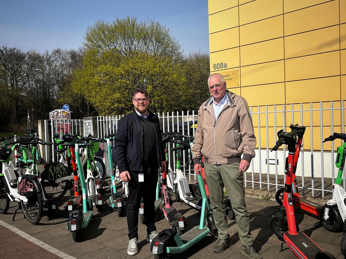 Friedrich Jeschke (li., Volt) und Klaus Reinartz (FDP) inmitten der wild abgestellten E-Scootern nach FC-Spielen