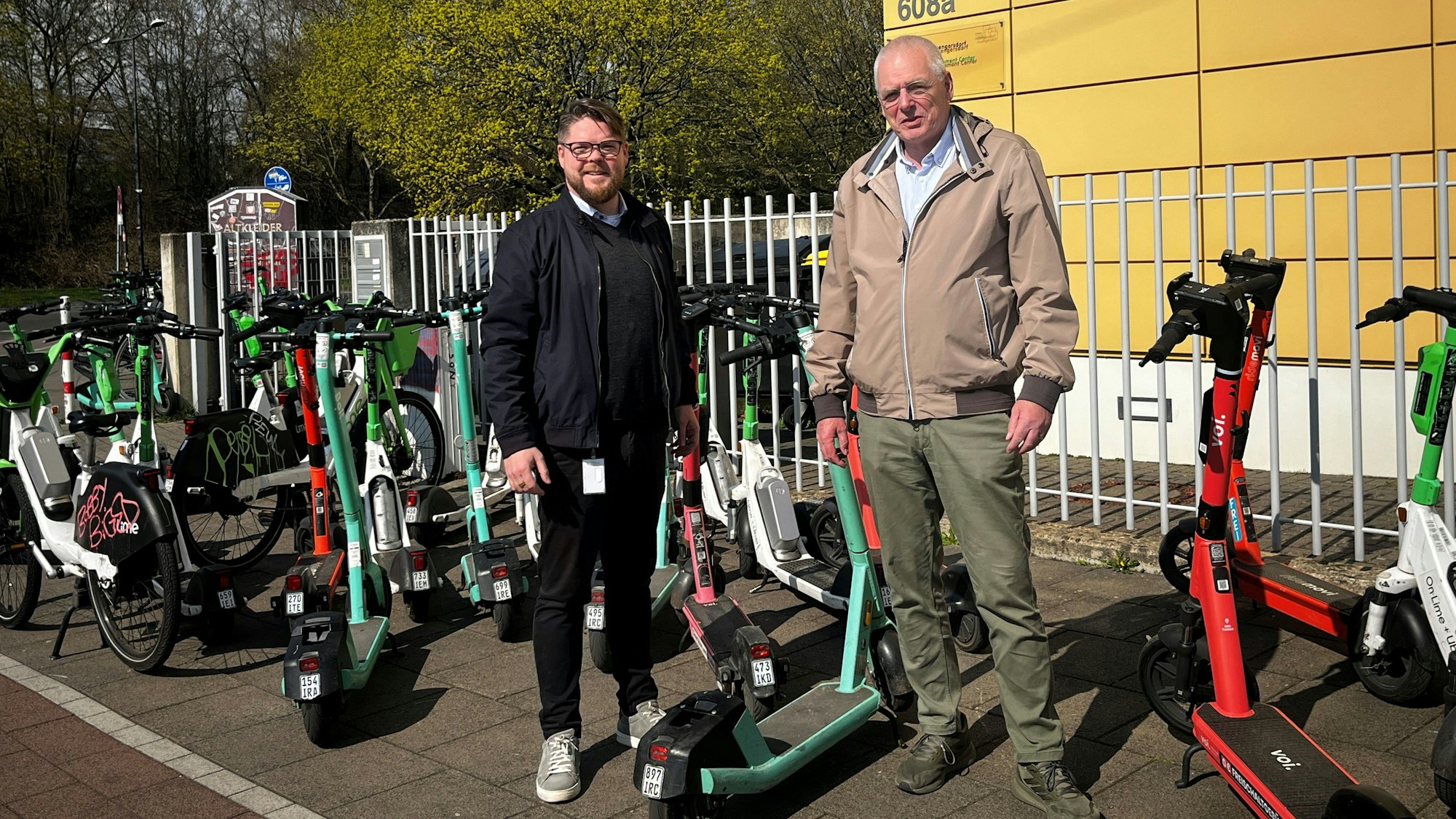 Friedrich Jeschke (li., Volt) und Klaus Reinartz (FDP) inmitten der wild abgestellten E-Scootern nach FC-Spielen