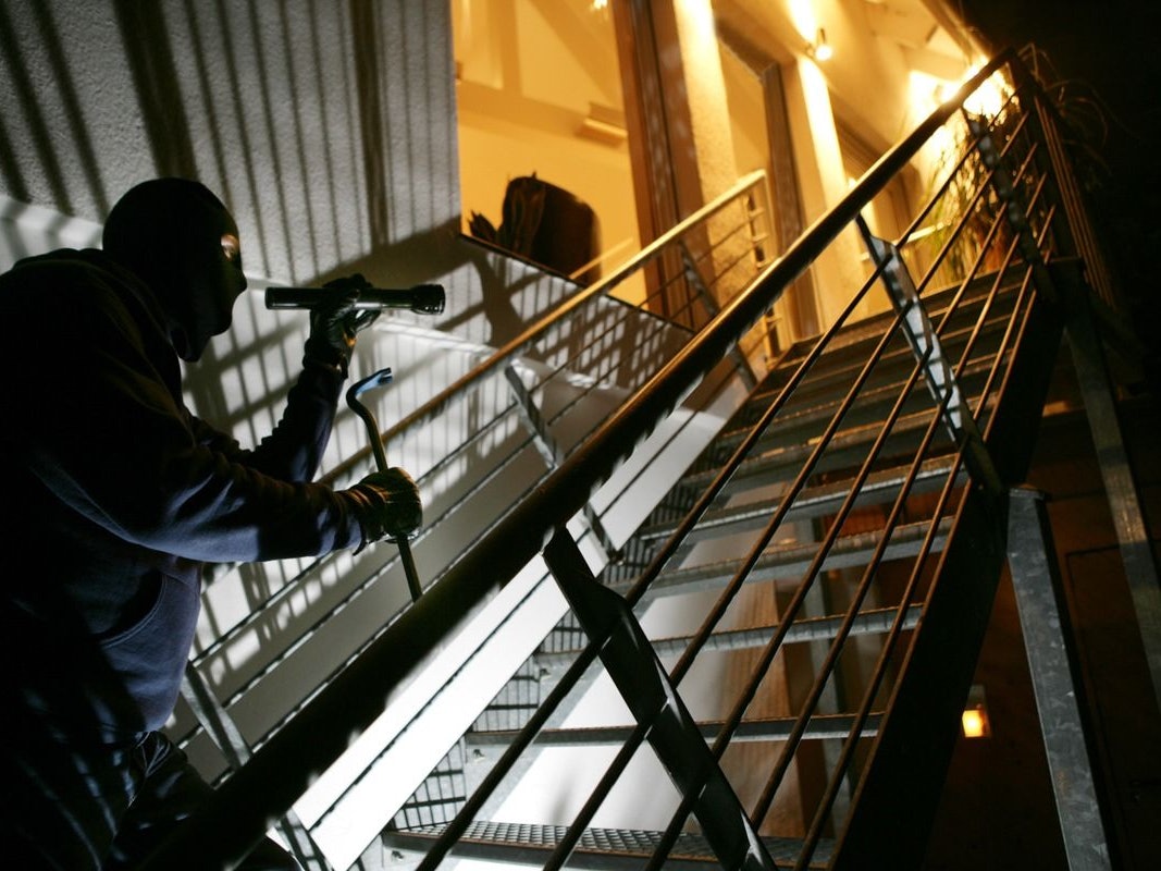 Einbrecher steigt eine Treppe hinauf.