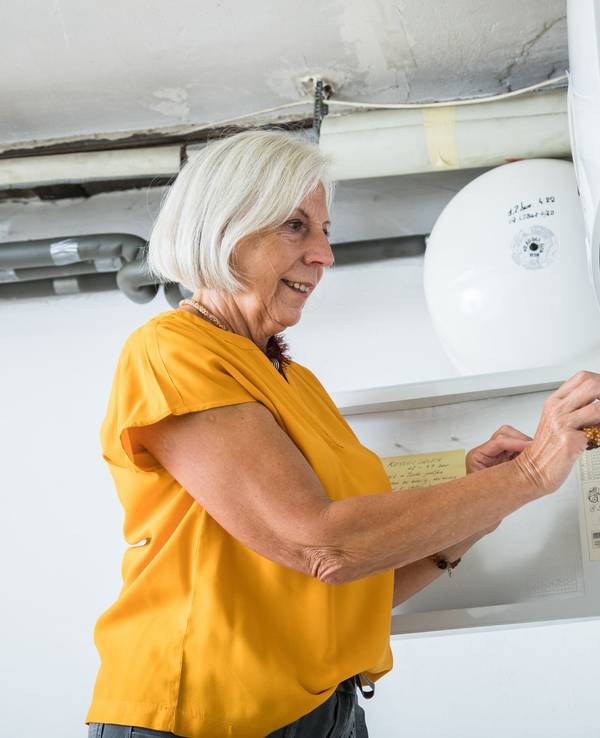 Eine Frau bedient die Zeitschaltuhr einer Heizungsanlage