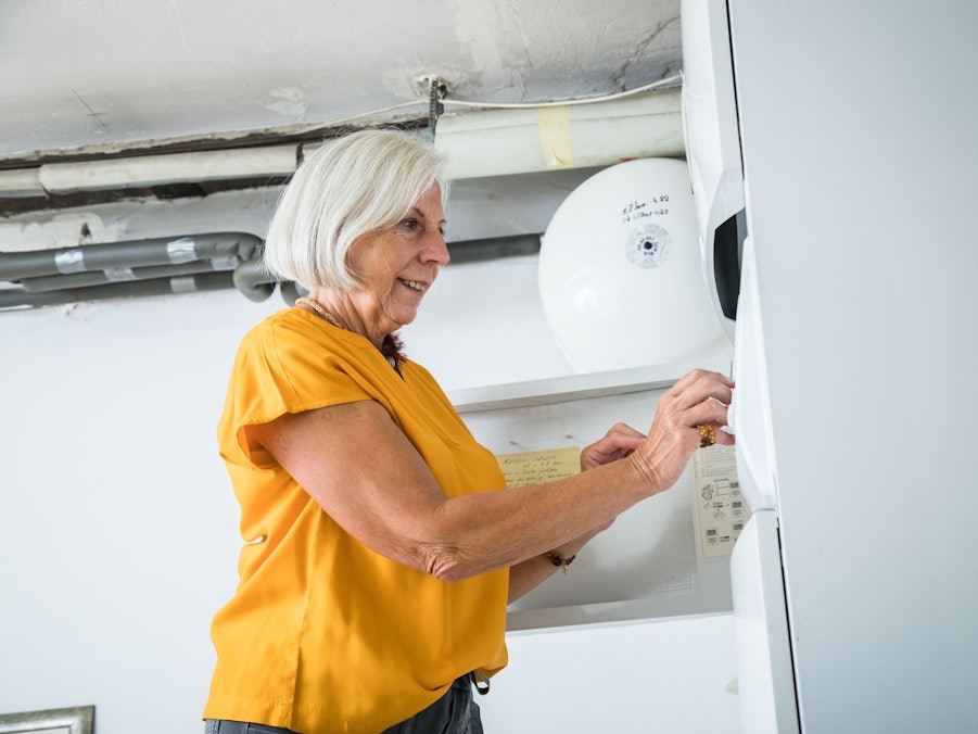Eine Frau bedient die Zeitschaltuhr einer Heizungsanlage