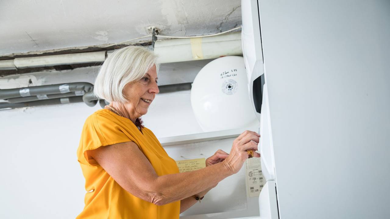 Eine Frau bedient die Zeitschaltuhr einer Heizungsanlage