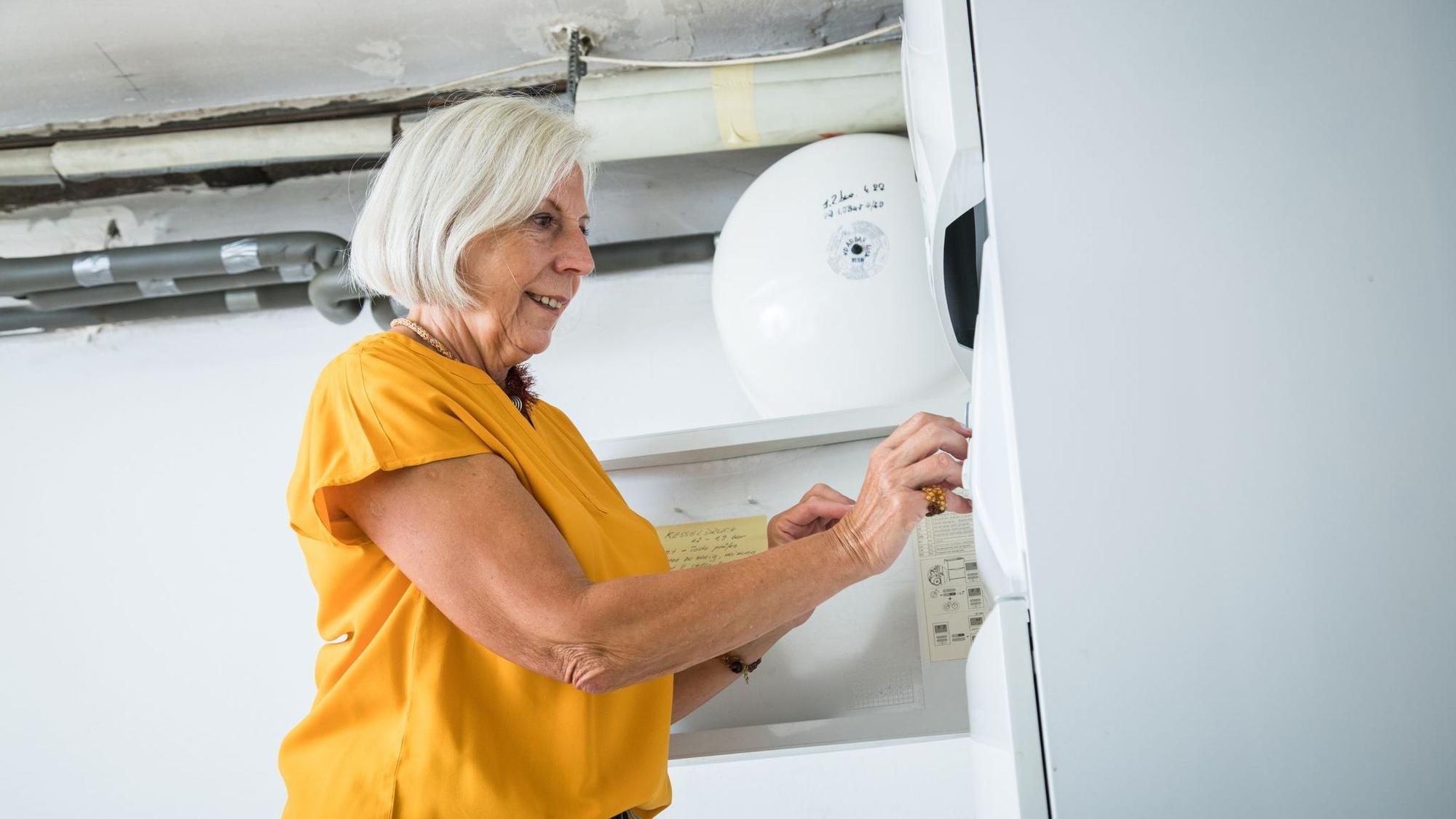 Eine Frau bedient die Zeitschaltuhr einer Heizungsanlage