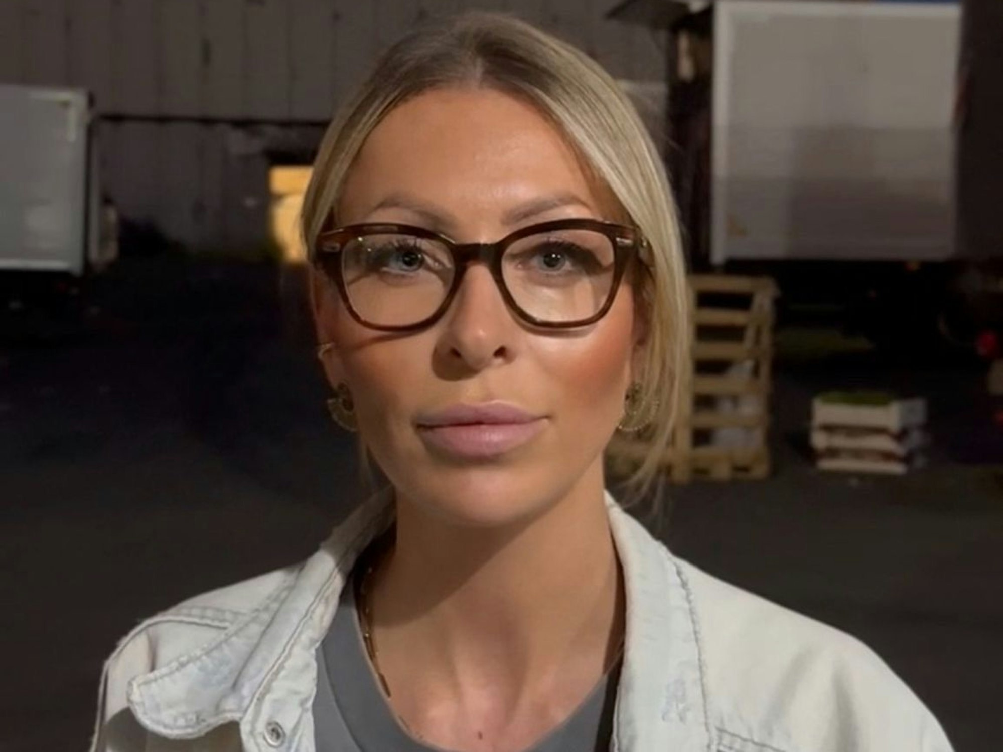 Eine Frau steht vor einer Wellblechhalle.