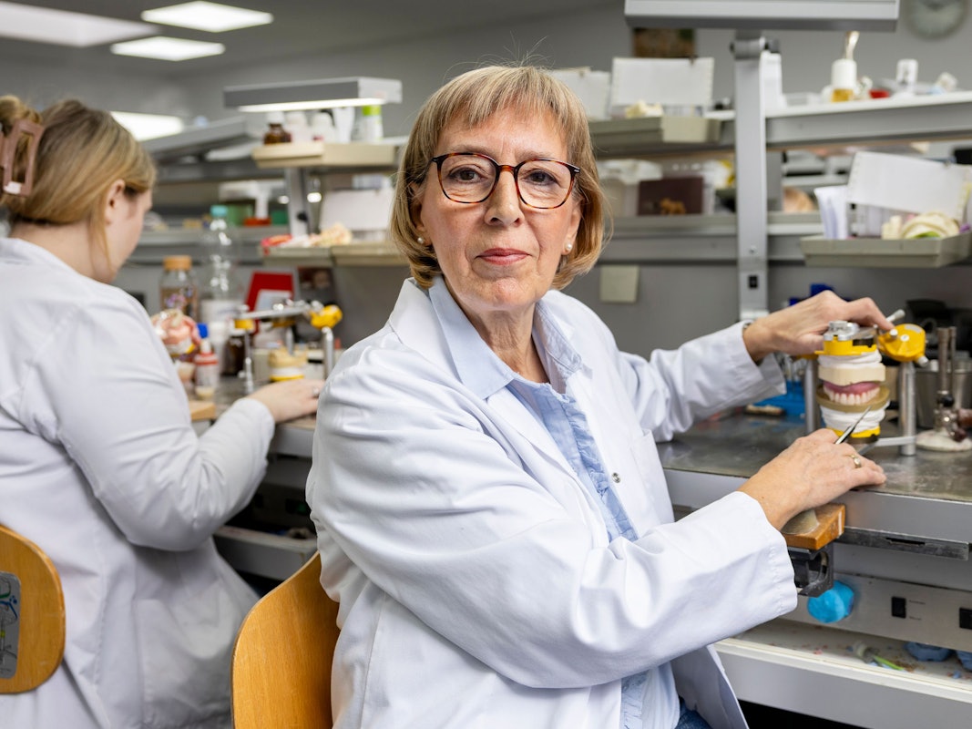 Gabriele Lachmann sitzt an ihrem Arbeitsplatz im Dentallabor vor einer Zahnprotese, an der sie gerade arbeitet.
