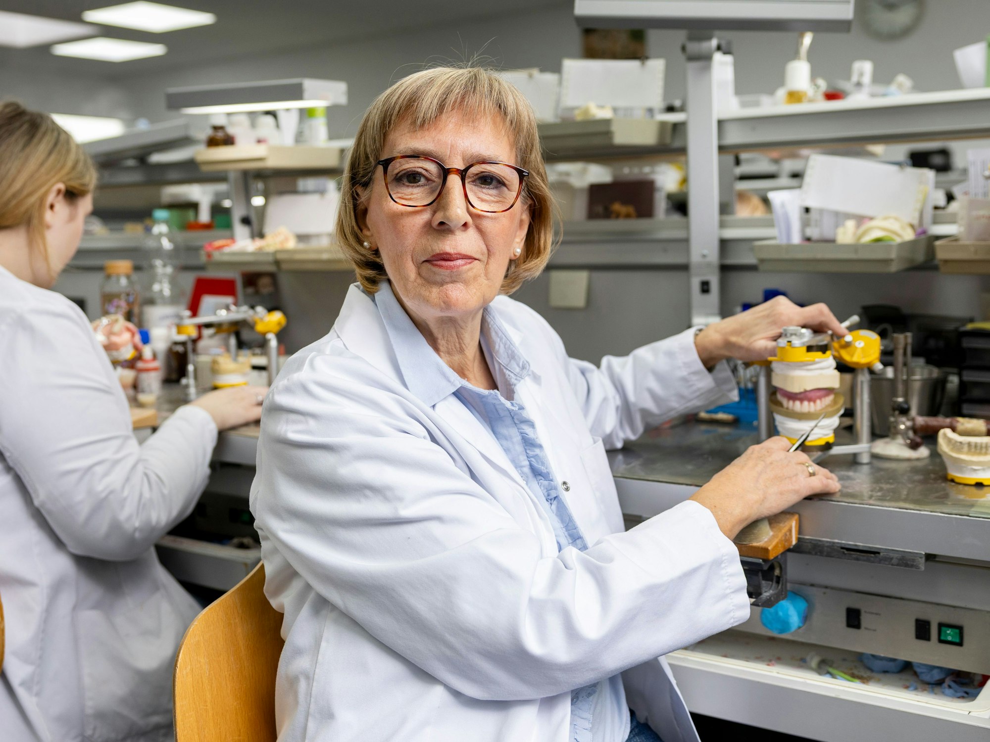 Gabriele Lachmann sitzt an ihrem Arbeitsplatz im Dentallabor vor einer Zahnprotese, an der sie gerade arbeitet.