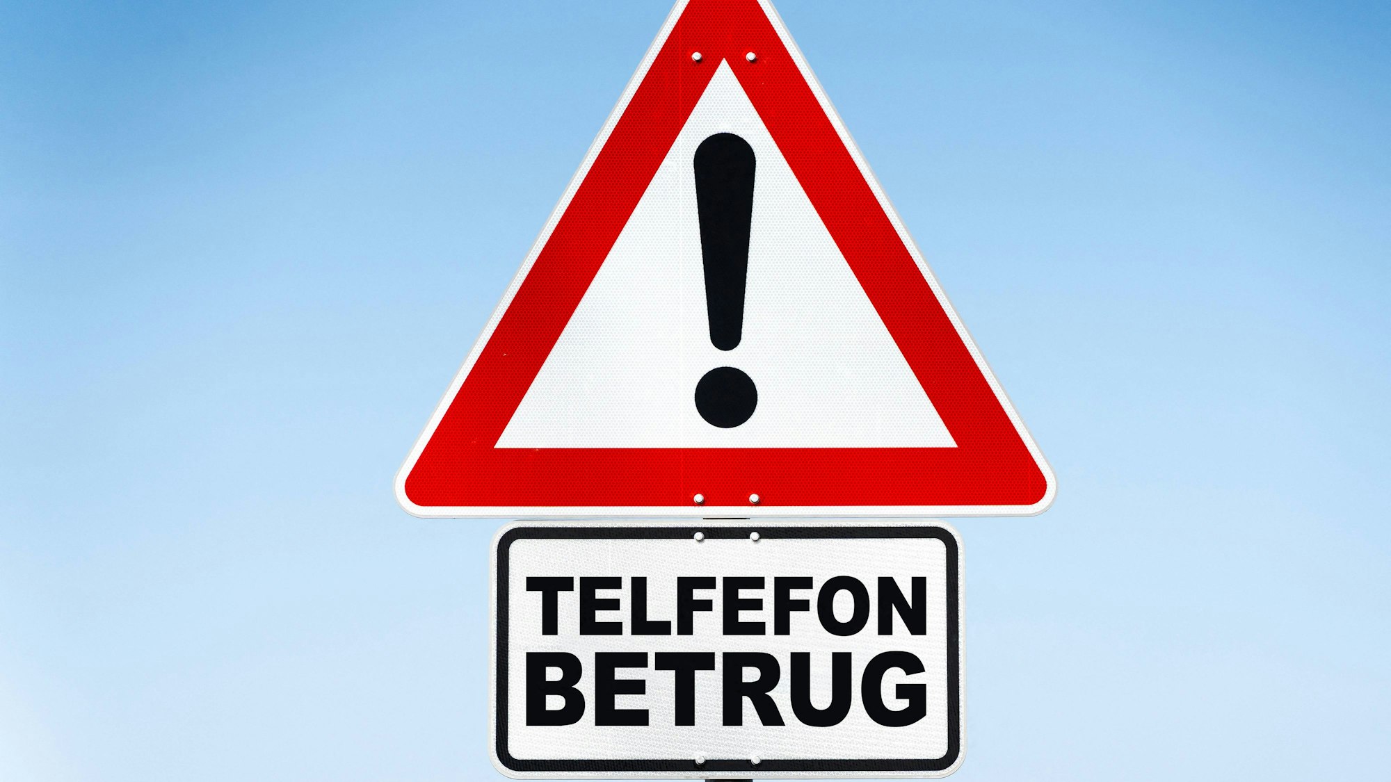Warnschild mit Aufschrift Telefonbetrug vor blauem Himmel