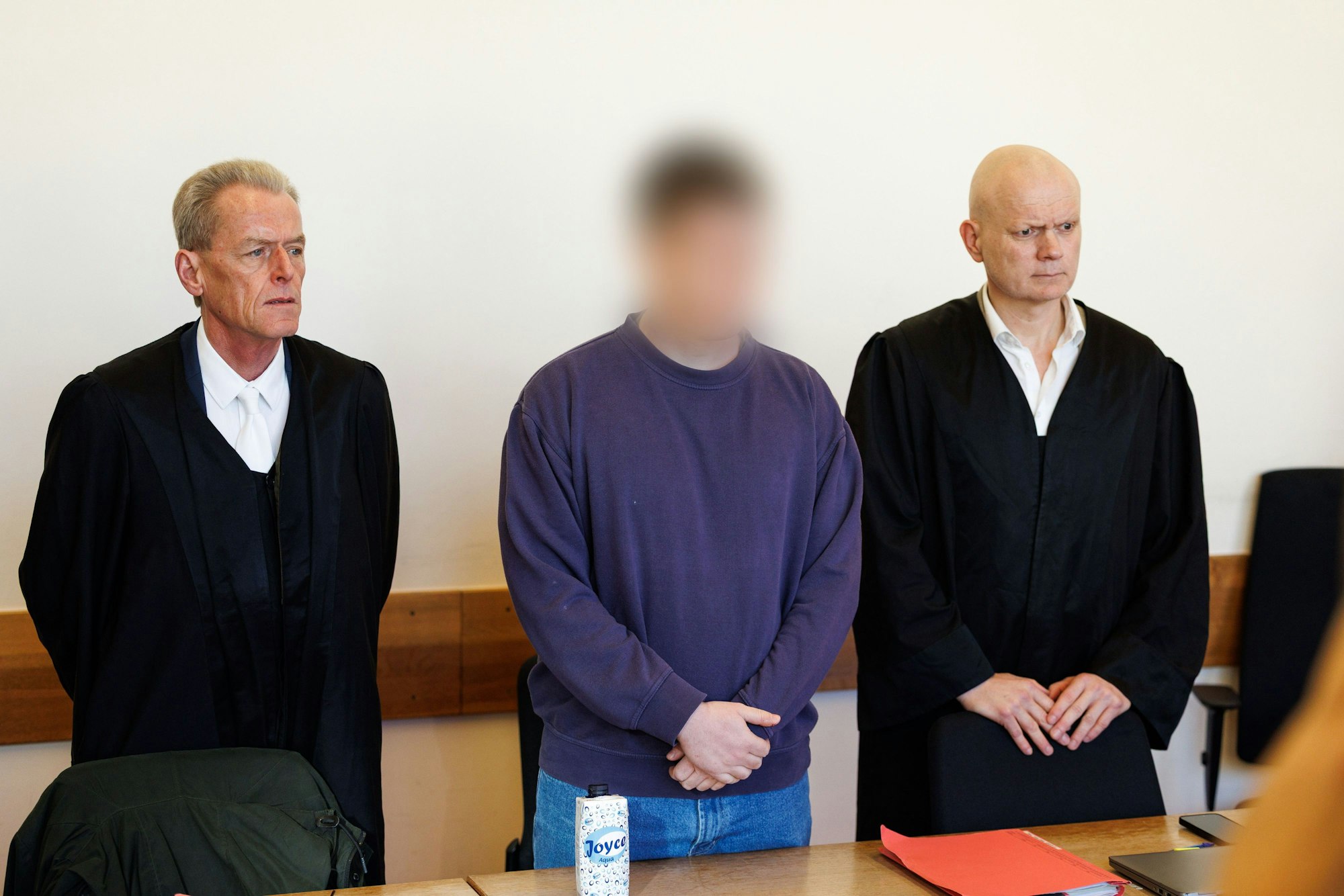 Der Angeklagte (M) steht neben seinen Verteidigern Helmut Wöhler (l) und Jerrit Schöll in einem Saal vom Landgericht Detmold zu Beginn eines Mordprozesses nach tödlichem Messerangriffs auf 16-Jährigen in einem Supermarkt in Lemgo.