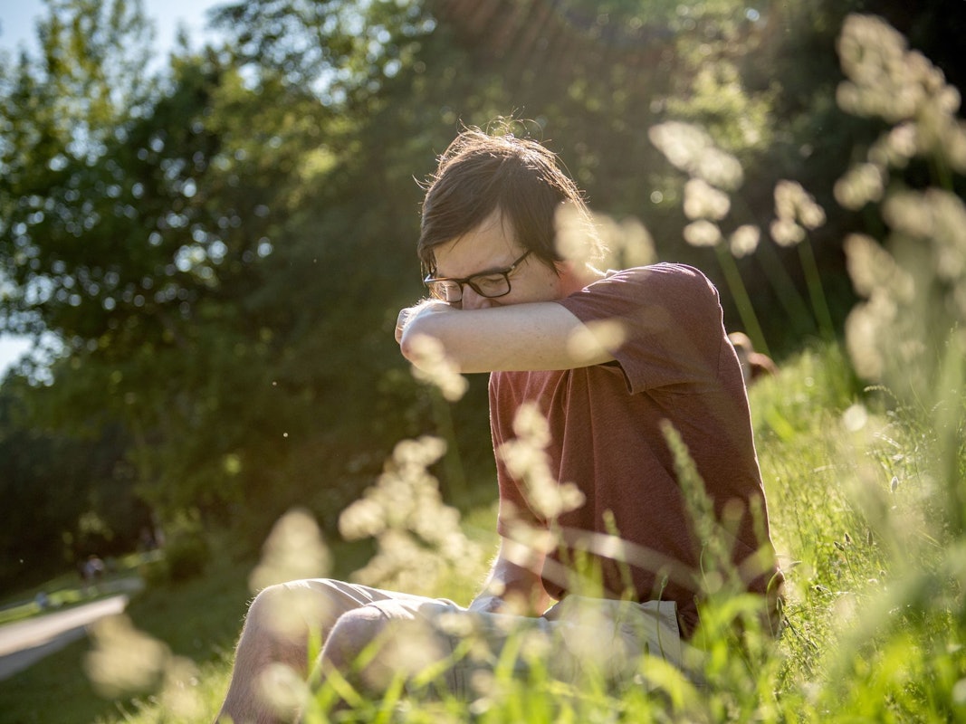 Mann in einem Park niest