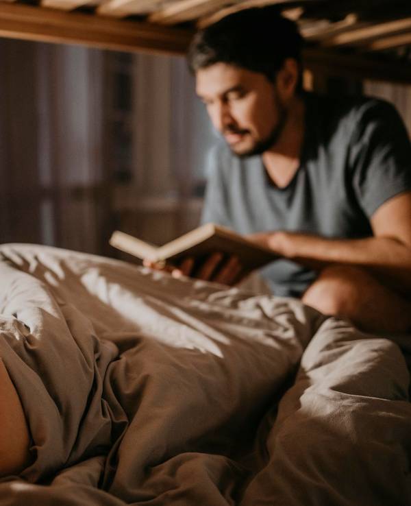 Vater liest seinen Kindern bei der Einschlafbegleitung etwas vor