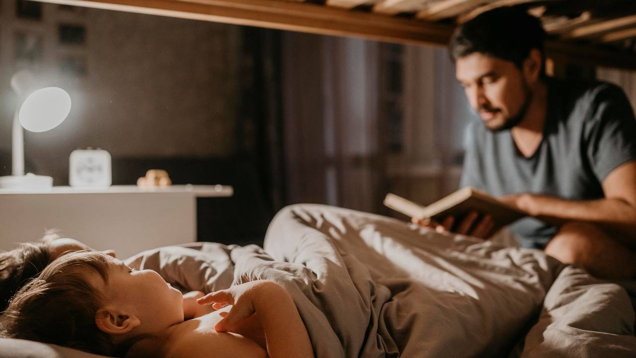 Vater liest seinen Kindern bei der Einschlafbegleitung etwas vor