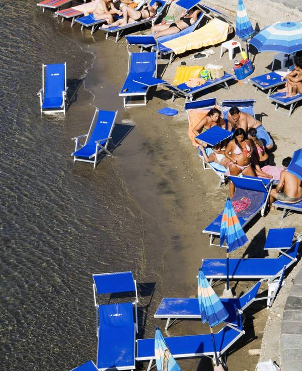 Urlauber liegen in Italien am Strand.
