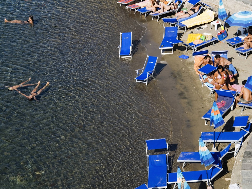 Urlauber liegen in Italien am Strand.