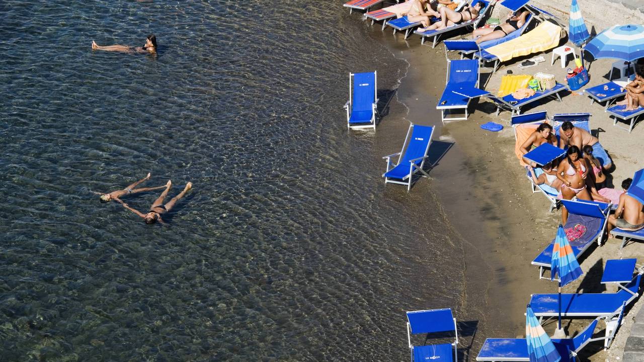 Urlauber liegen in Italien am Strand.