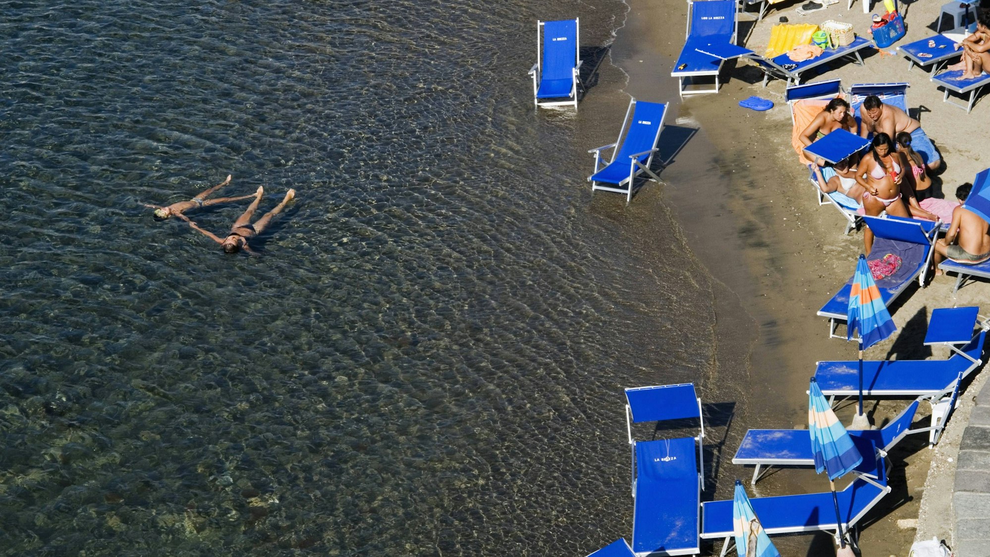 Urlauber liegen in Italien am Strand.