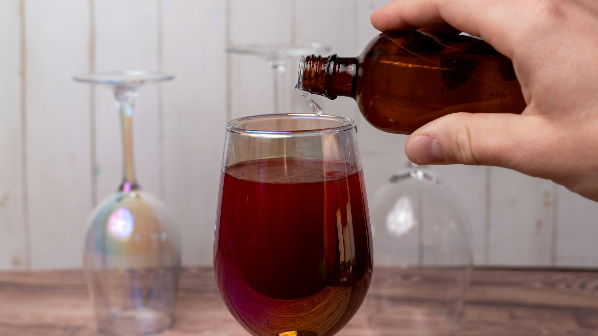 Hand gießt heimlich Flüssigkeit in Getränk