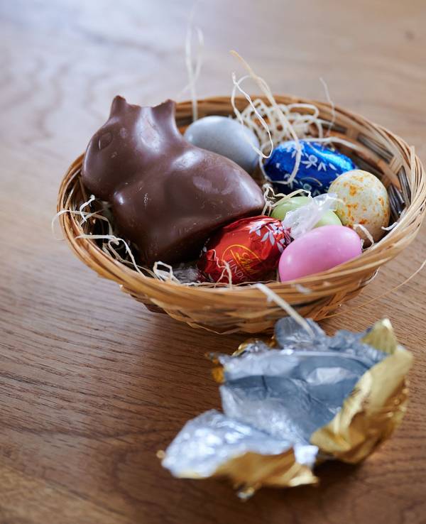 Ein Schokoladenhase liegt mit Eiern in einem Osternest