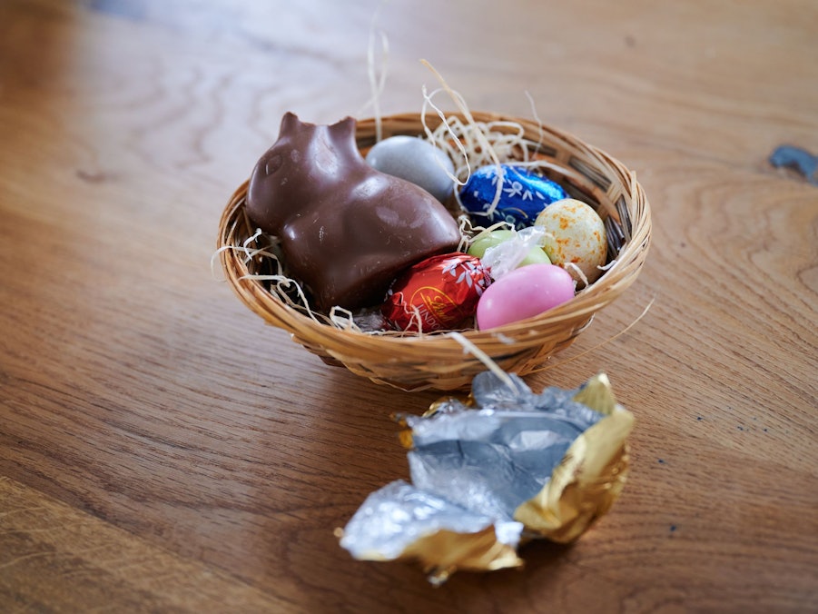 Ein Schokoladenhase liegt mit Eiern in einem Osternest