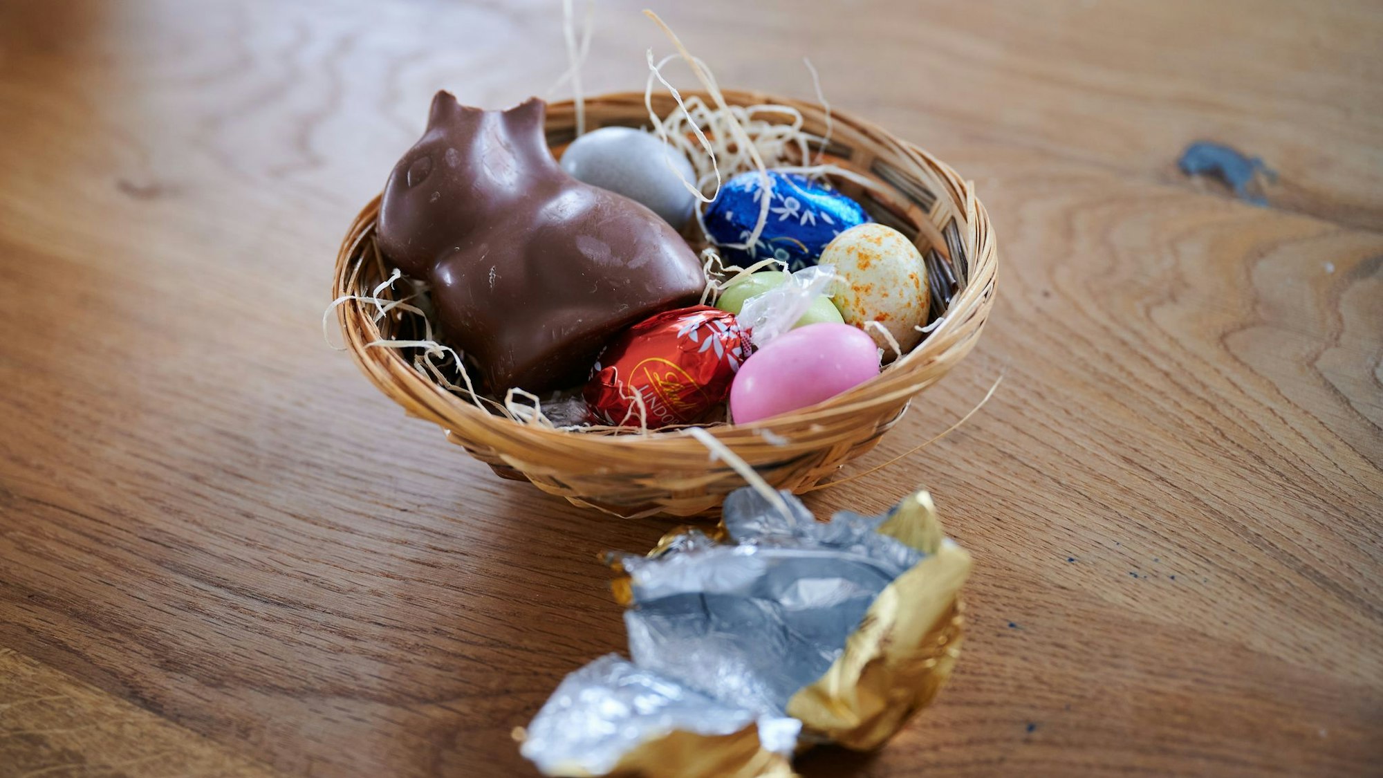 Ein Schokoladenhase liegt mit Eiern in einem Osternest