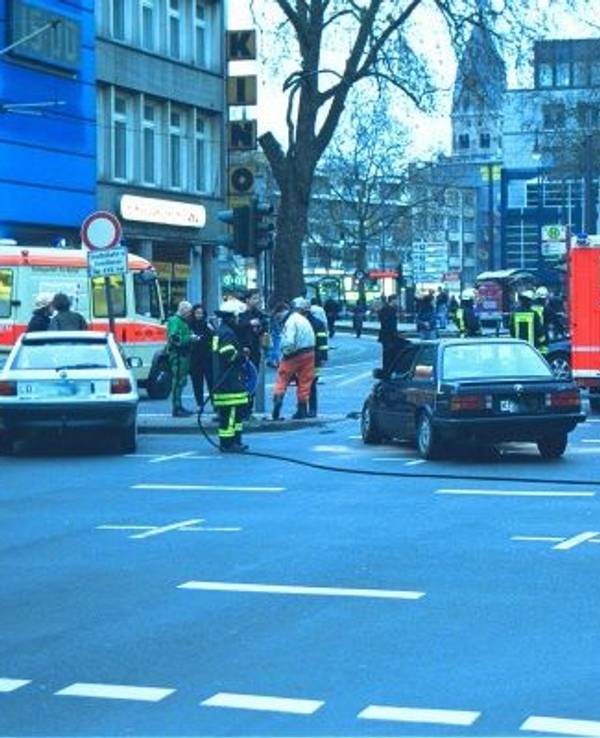 Zwei verunglückte Autos stehen auf einer Straße, um sie herum Einsatzkräfte sowie Fahrzeuge von Rettungsdienst und Feuerwehr.