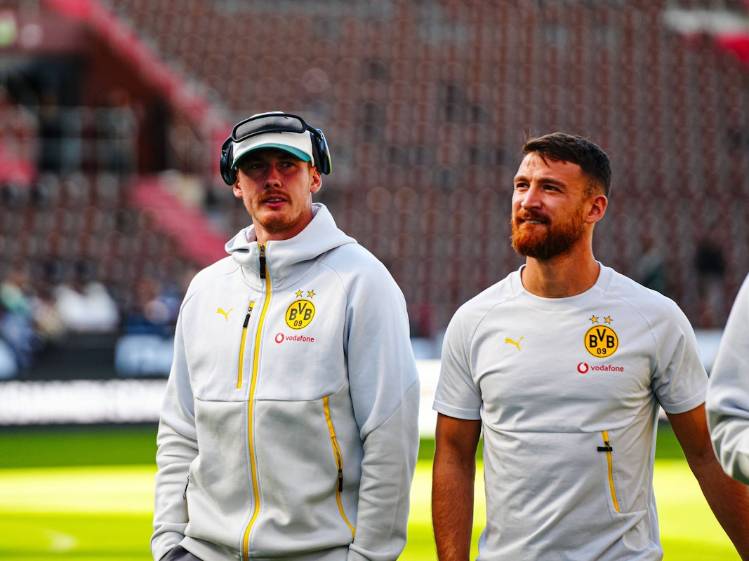 Julian Brandt und Salih Özcan (r.) gehen vor dem Spiel über den Platz.
