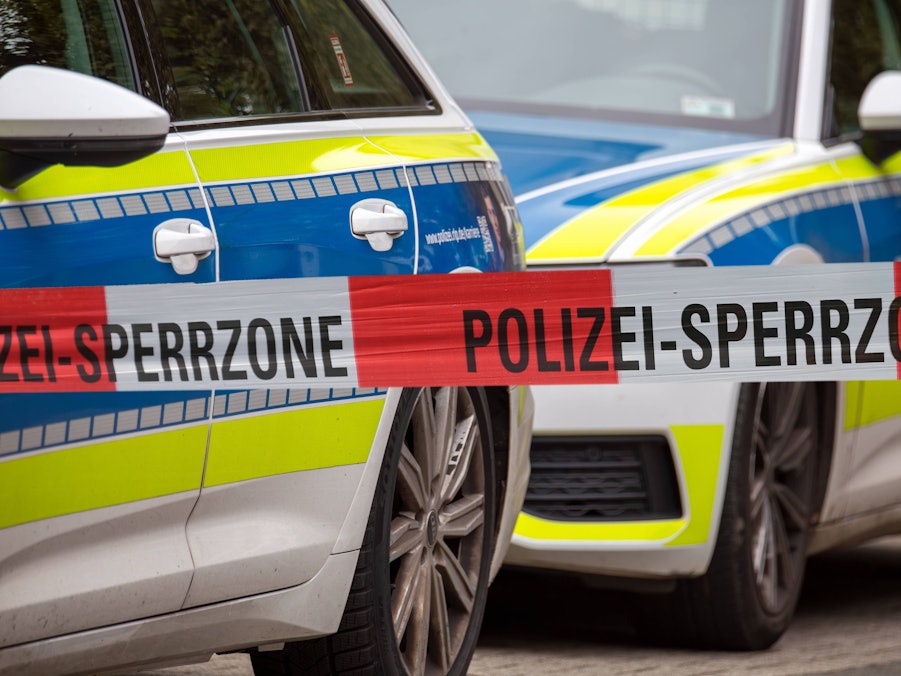 Polizei Absperrband vor Einsatzfahrzeugen