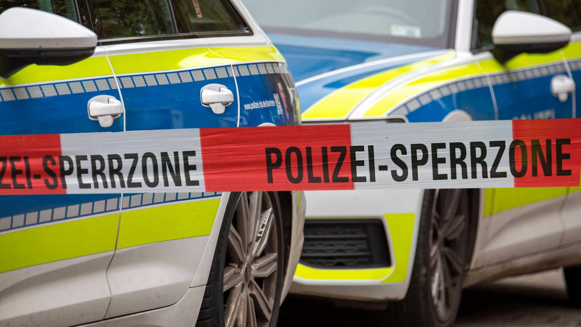Polizei Absperrband vor Einsatzfahrzeugen