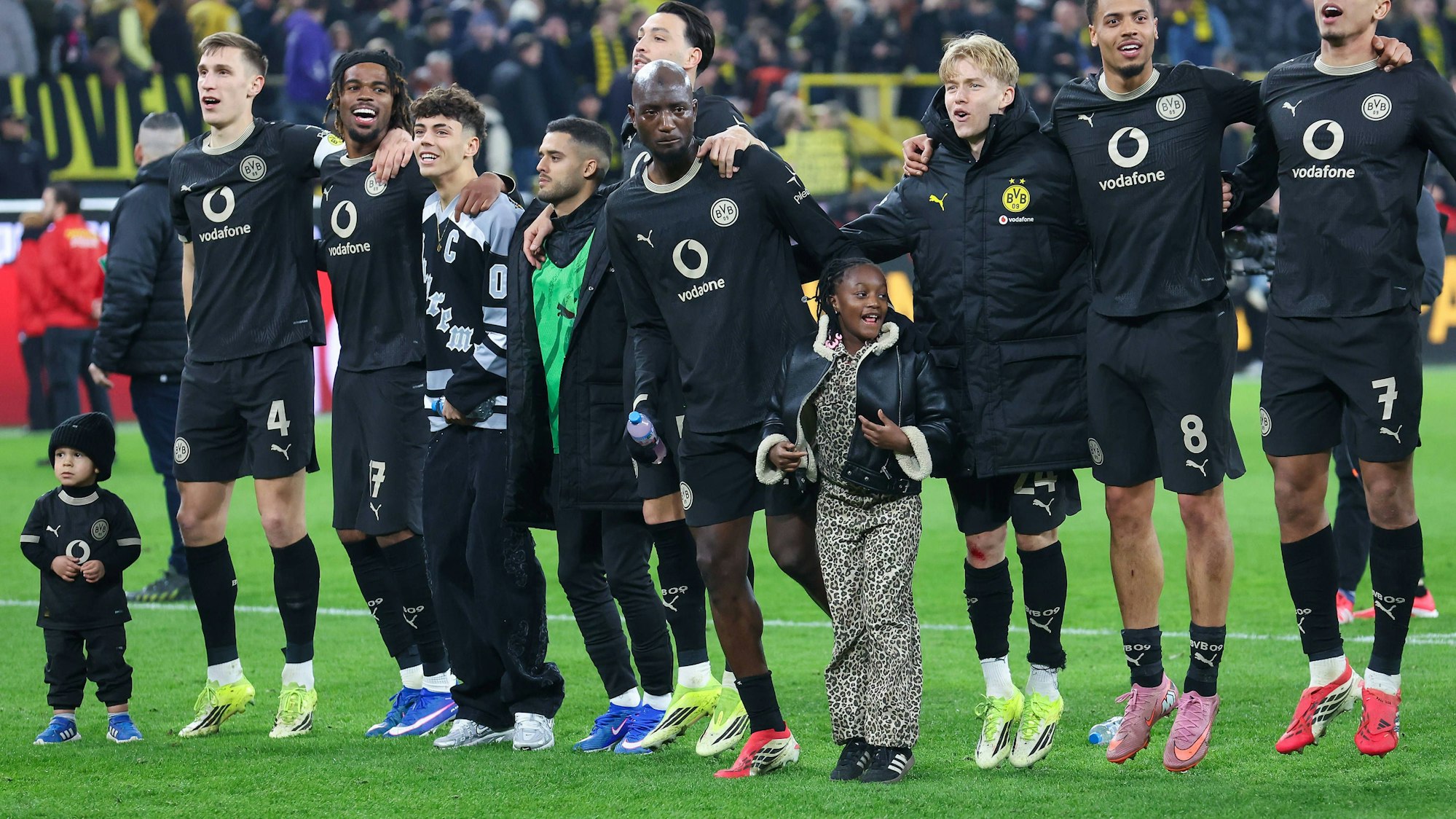 Spieler von Borussia Dortmund feiern mit ihren Kindern vor de Fankurve.