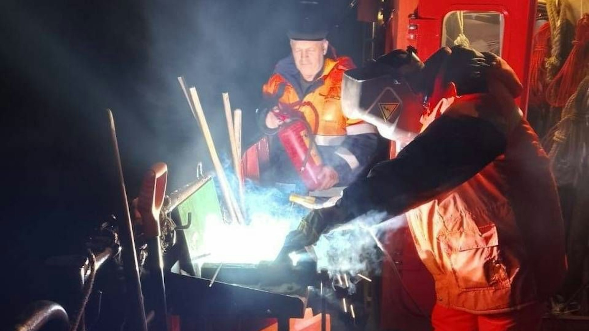 Zwei Männer schweißen und halten Feuerlöscher