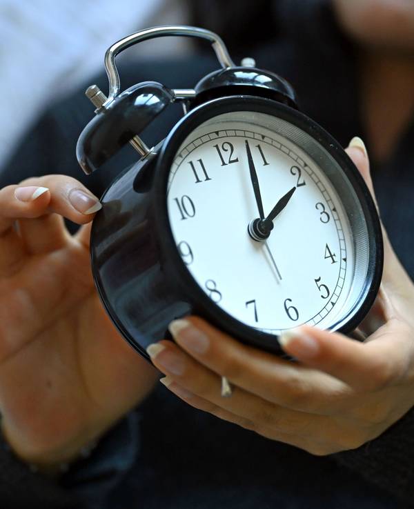 Eine Frau hält einen Wecker in der Hand. Am 29. März 2026 hat die Sommerzeit begonnen.
