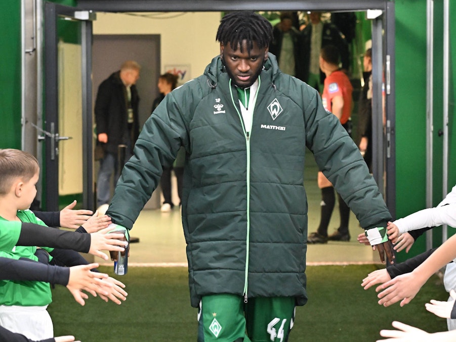 Victor Boniface klatscht mit Einlaufkindern von Werder Bremen ab.